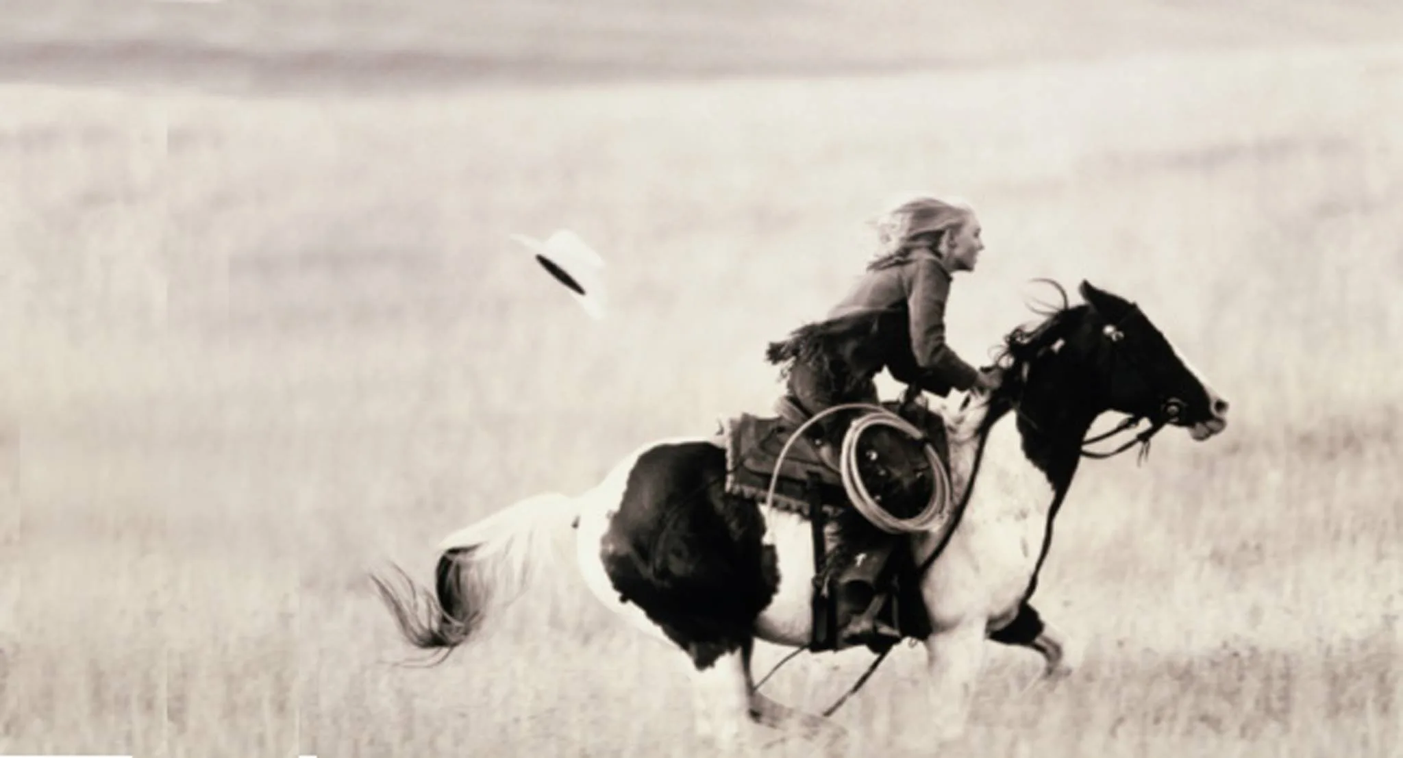 Girl riding a horse with her hat flying